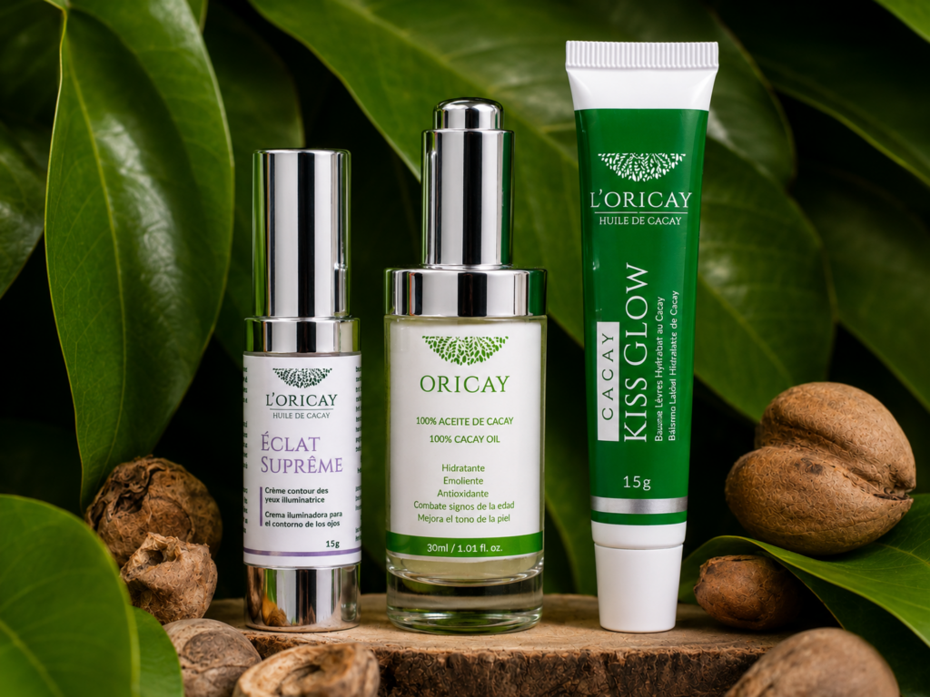 Aceite de Cacay, Eclat Supreme y Kiss Glow de L'ORICAY sobre madera rodeados de nueces y hojas de Cacay